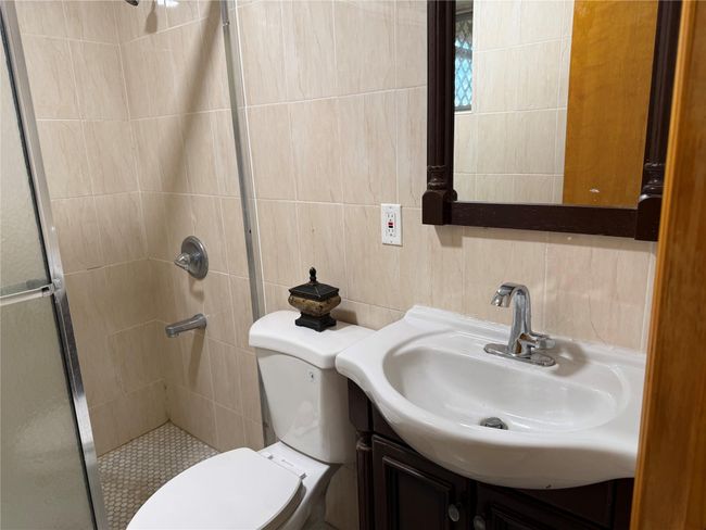 Bathroom with a shower stall, toilet, vanity, and tile walls | Image 18