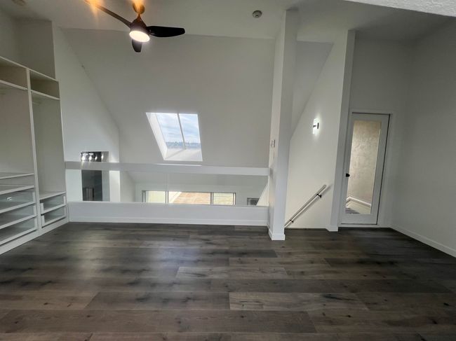 Unfurnished living room featuring a skylight, vaulted ceiling, dark wood-style flooring, and a ceiling fan | Image 6