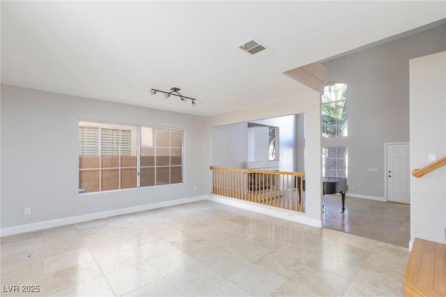 Unfurnished room with a towering ceiling, baseboards, rail lighting, light tile patterned floors, and visible vents | Image 6