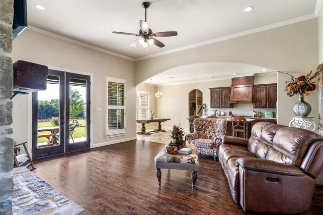 Living area with arched walkways, a ceiling fan, dark wood-type flooring, crown molding, and recessed lighting | Image 11