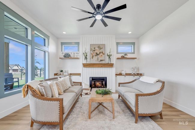 Living room featuring a large fireplace, ceiling fan, wood finished floors, and recessed lighting | Image 4