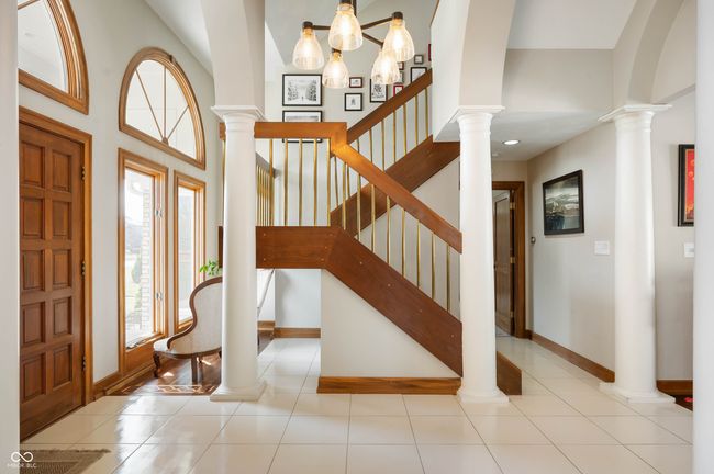 tiled foyer featuring decorative columns, baseboards, and a towering ceiling | Image 7
