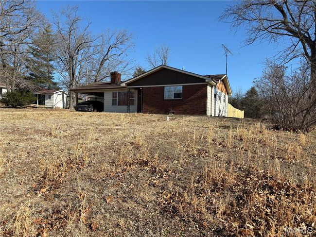 View of front of house featuring an attached carport, brick siding, and a chimney | Image 6