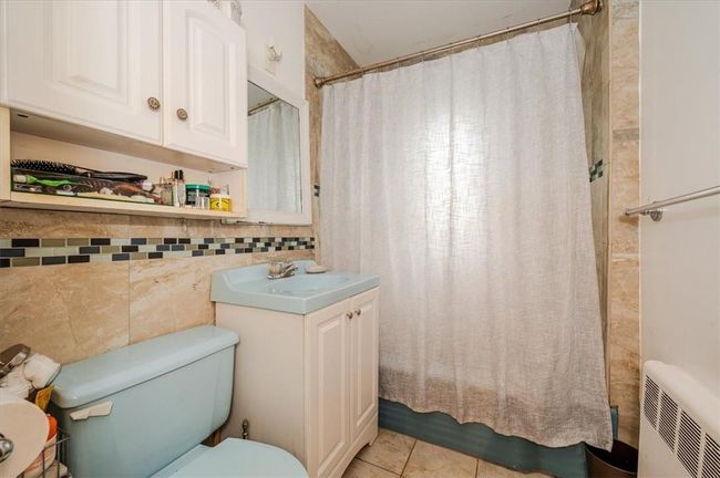Bathroom with tile walls, radiator, tile patterned floors, toilet, and vanity | Image 11
