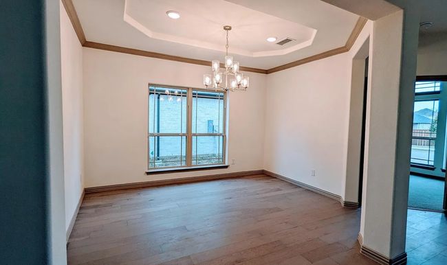 Spare room featuring a tray ceiling, visible vents, baseboards, a chandelier, and hardwood / wood-style flooring | Image 5