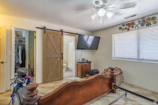 Bedroom with a barn door, a textured ceiling, a walk in closet, ensuite bathroom, and a closet | Image 33