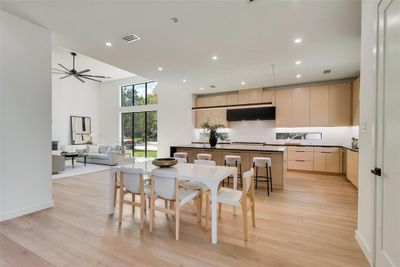 Dining area featuring light hardwood / wood-style flooring, a high ceiling, and ceiling fan | Image 1