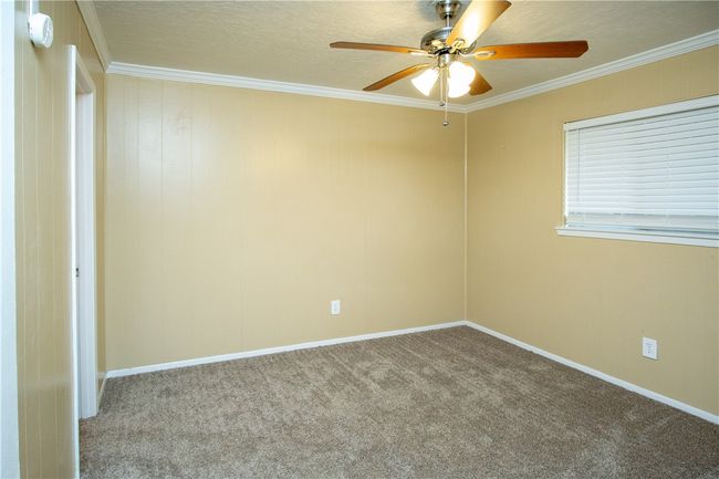 Spare room featuring ceiling fan, carpet flooring, crown molding, and a smoke detector | Image 5