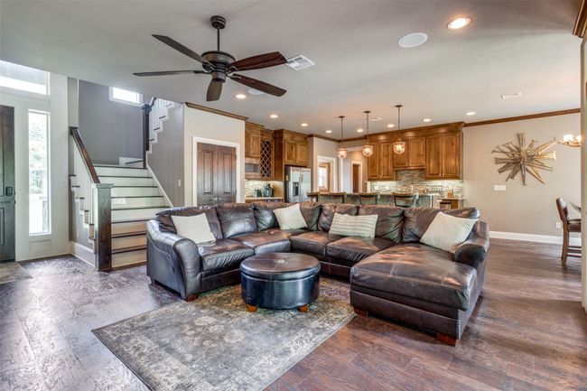 Living room featuring hardwood / wood-style floors, plenty of natural light, ornamental molding, and ceiling fan with notable chandelier | Image 4