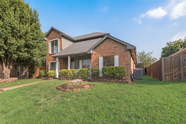 Traditional home with brick siding, a shingled roof, and covered porch | Image 18