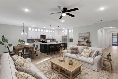 Living room with ceiling fan with notable chandelier, light hardwood / wood-style flooring, and sink | Image 2