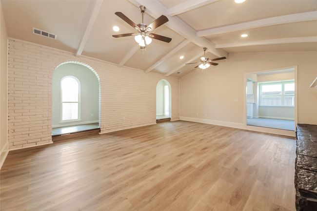Unfurnished living room featuring arched walkways, brick wall, ceiling fan, light wood-style floors, and recessed lighting | Image 5