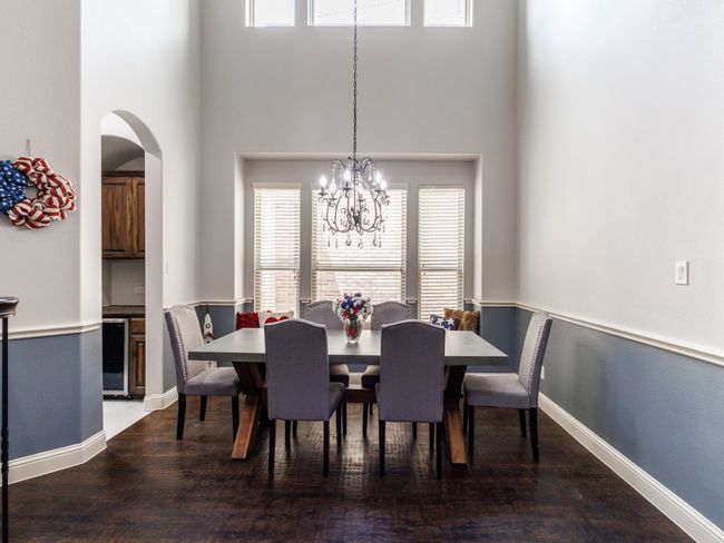A sun-filled formal dining area adorned by a chandelier and large windows. | Image 8