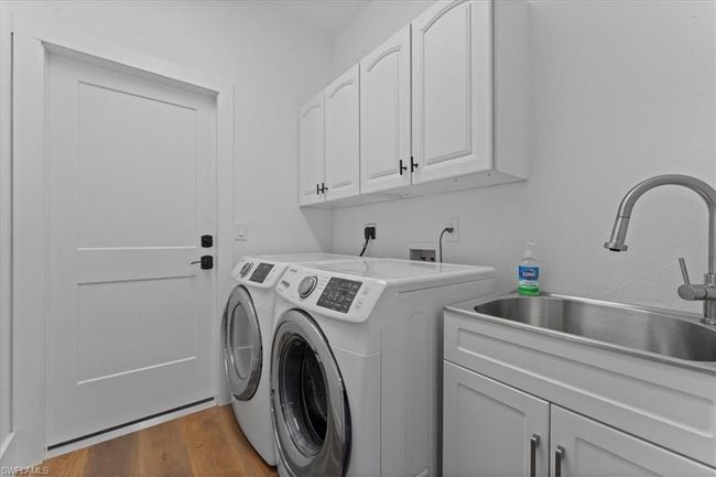Washroom featuring cabinet space, washing machine and clothes dryer, and dark wood-style flooring | Image 32