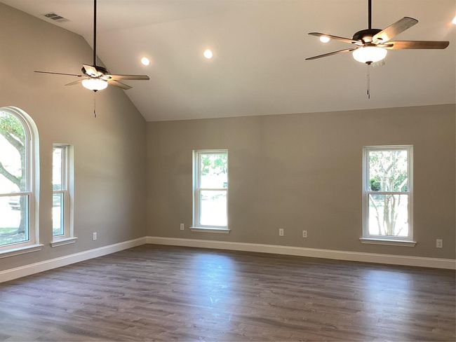 Empty room with ceiling fan, dark wood-style floors, high vaulted ceiling, and recessed lighting | Image 24