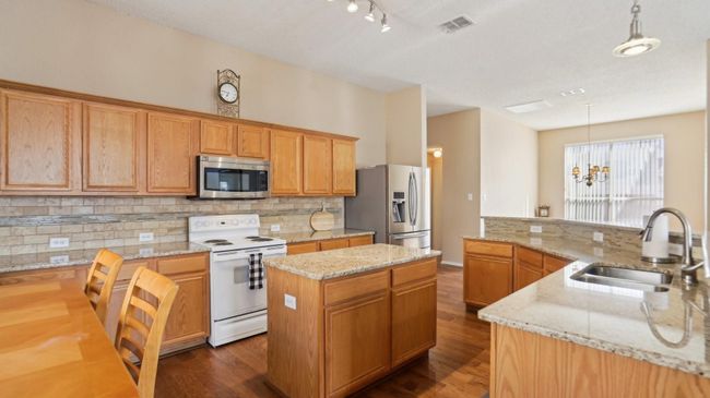 The kitchen features an abundance of cabinet and counter space, with a center island and a breakfast bar - perfect for entertaining! | Image 10