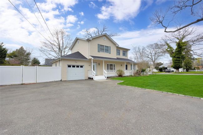 Traditional-style home featuring aphalt driveway, fence, a front lawn, an attached garage, and a porch | Image 16