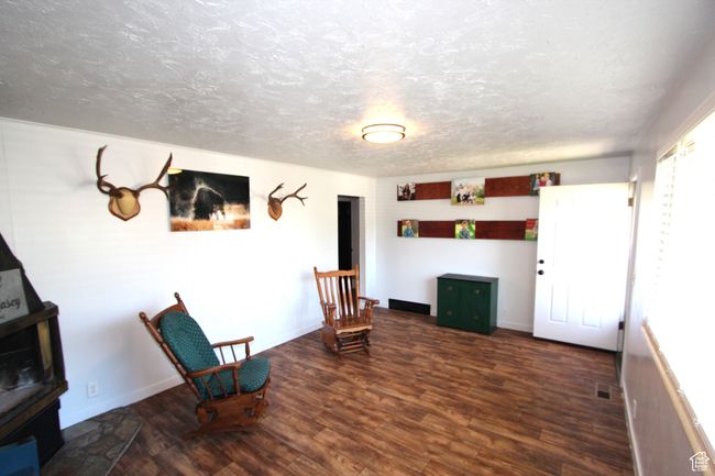 Unfurnished room with wood finished floors, a textured ceiling, and a wood stove | Image 10