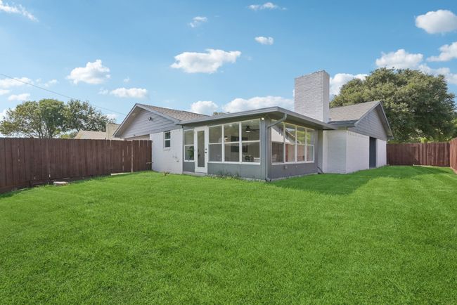Rear view of property with a chimney, a sunroom, a fenced backyard, and brick siding | Image 39