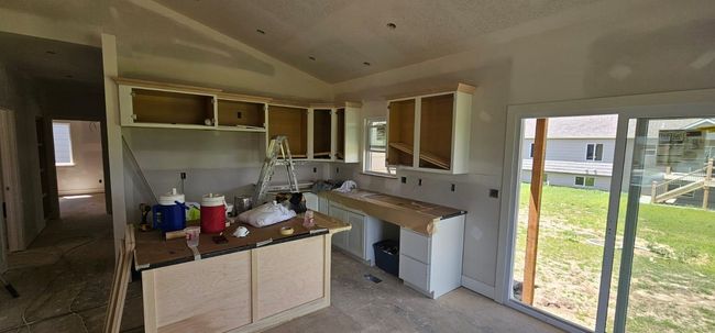 Kitchen featuring vaulted ceiling, open shelves, and concrete floors | Image 4