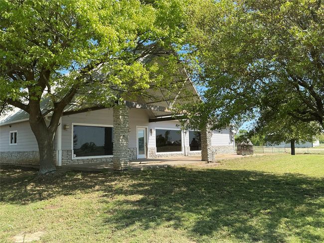 Back of property featuring stone siding, a lawn, and fence | Image 22