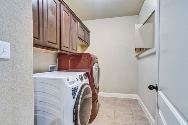 Washroom with independent washer and dryer, cabinet space, and light tile patterned flooring. Includes a large sink. | Image 17
