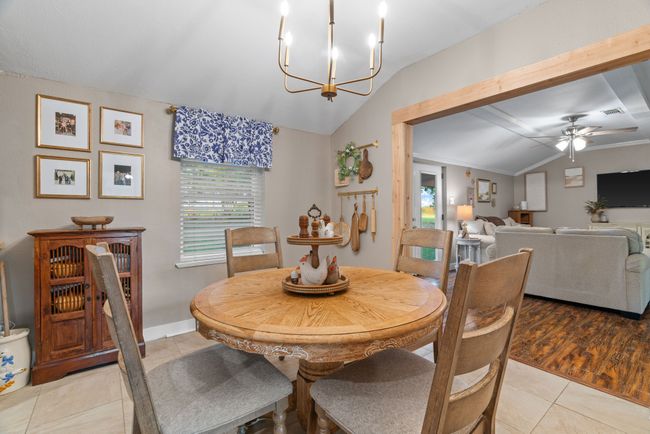 Dining space featuring lofted ceiling, ceiling fan, light tile patterned flooring, and a chandelier | Image 9