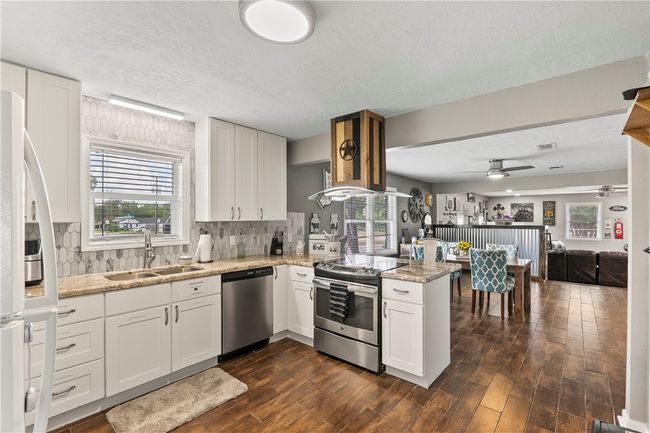 Kitchen with appliances with stainless steel finishes, a peninsula, decorative backsplash, ceiling fan, and a textured ceiling | Image 10