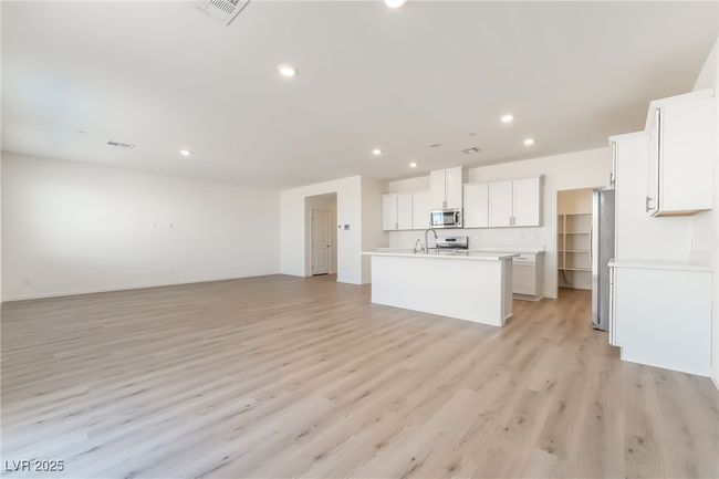 Kitchen with appliances with stainless steel finishes, open floor plan, an island with sink, light wood-type flooring, and light countertops | Image 9