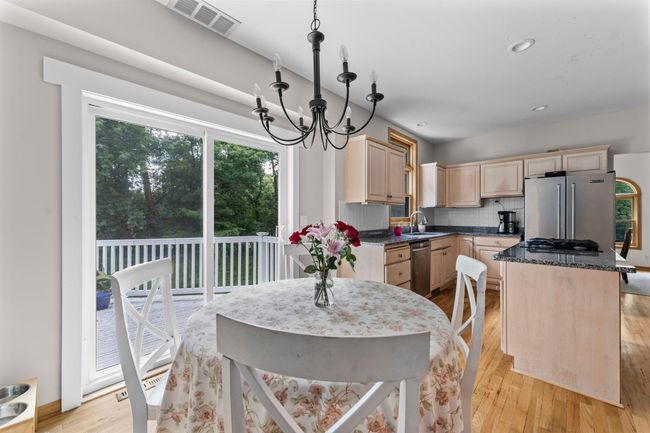 This space seamlessly connects to the informal dining room, which continues the wood flooring and features statement lighting and sliding glass doors that open to the deck—making indoor-outdoor living a breeze. | Image 9