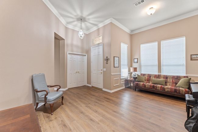Foyer entrance featuring light wood-style floors, ornamental molding, baseboards, and a chandelier | Image 7