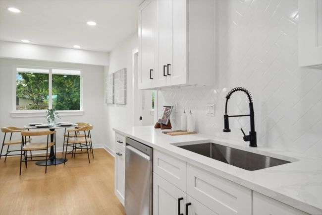 Kitchen featuring light wood-type flooring, a sink, white cabinets, decorative backsplash, and dishwasher | Image 10