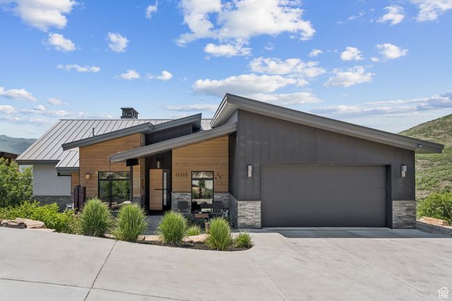 Contemporary house with stone siding, concrete driveway, a garage, a standing seam roof, and a metal roof | Image 70