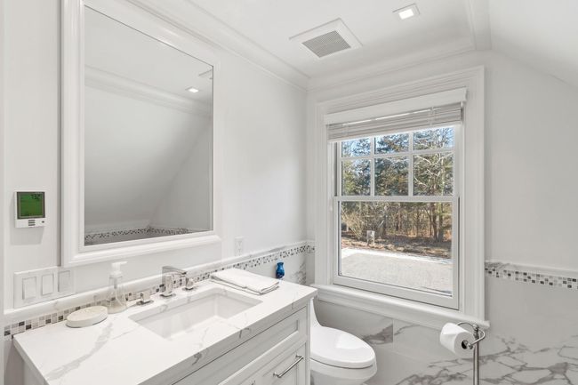 Bathroom featuring vanity, radiator, crown molding, vaulted ceiling, and toilet | Image 39