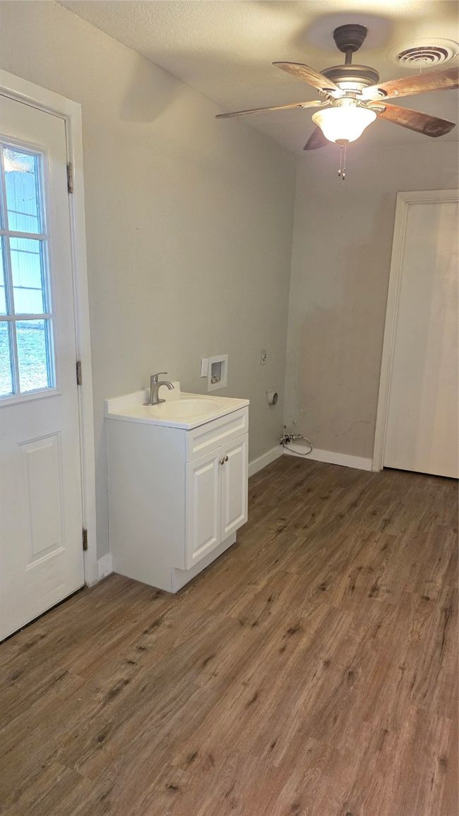 Laundry area featuring dark wood-style floors, hookup for a washing machine, and wash bin. | Image 19