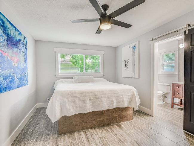 Bedroom featuring ceiling fan, ensuite bathroom, baseboards, and wood finished floors | Image 10