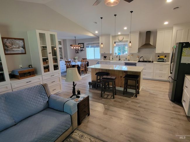 Living area with light wood-style flooring, a ceiling fan, recessed lighting, lofted ceiling, and a chandelier | Image 10