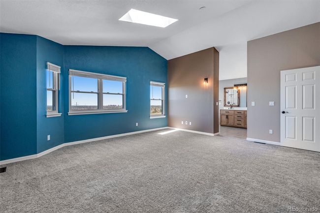 Unfurnished bedroom featuring visible vents, baseboards, connected bathroom, lofted ceiling with skylight, and carpet flooring | Image 16