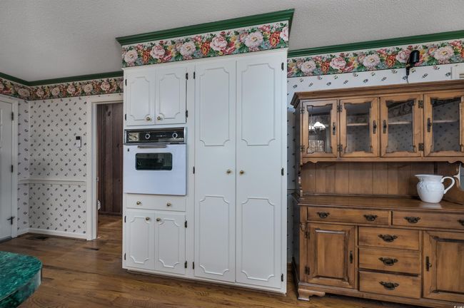 Kitchen featuring crown molding, a textured ceiling, white cabinets, white oven, and dark hardwood / wood-style floors | Image 16