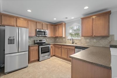 Kitchen with appliances with stainless steel finishes, crown molding, light tile patterned floors, tasteful backsplash, and sink | Image 2