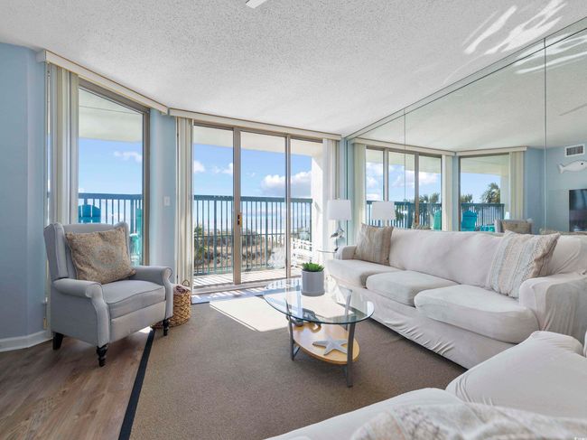 Living area featuring a wealth of natural light, a textured ceiling, wood finished floors, and expansive windows | Image 7
