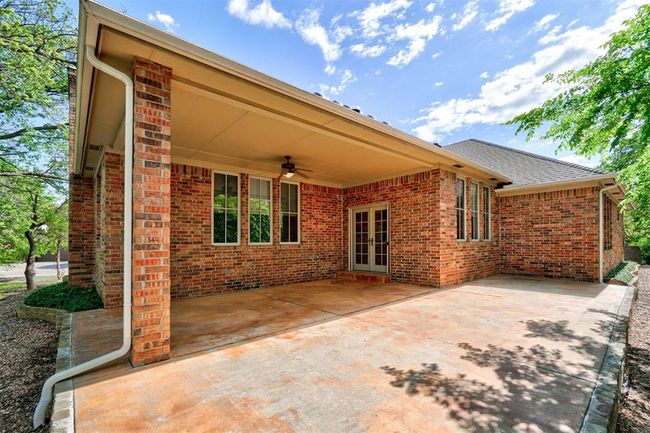 Rear view of property featuring a ceiling fan, a shingled roof, a patio area, french doors, and brick siding | Image 43
