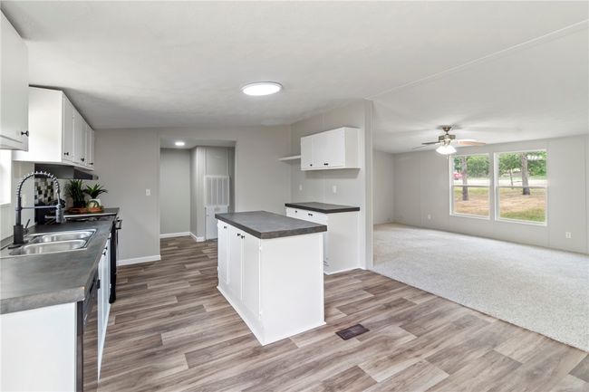 Kitchen featuring white cabinets, a sink, light wood-type flooring, dark countertops, and a ceiling fan | Image 20