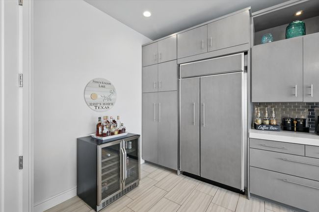 Kitchen with light countertops, beverage cooler, gray cabinets, paneled built in refrigerator, and decorative backsplash | Image 17