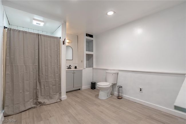 Bathroom with wood finished floors, vanity, toilet, a shower with curtain, and baseboards | Image 21