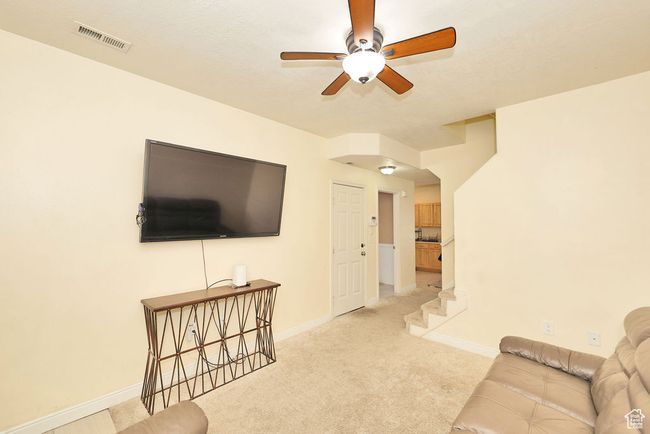 Living room featuring visible vents, baseboards, a ceiling fan, and light carpet | Image 20