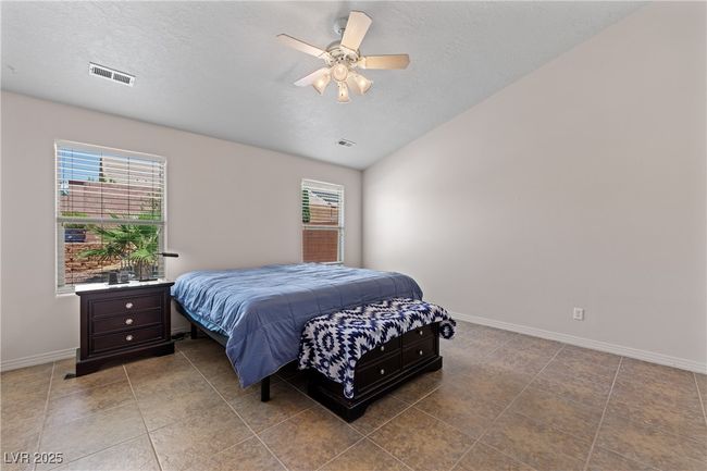 Bedroom featuring multiple windows, a ceiling fan, tile patterned floors, a textured ceiling, and vaulted ceiling | Image 23