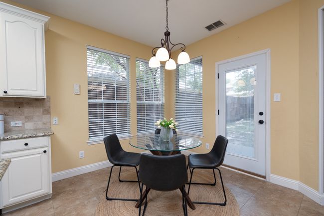 Dining space with a chandelier, light tile patterned floors, and healthy amount of natural light | Image 15
