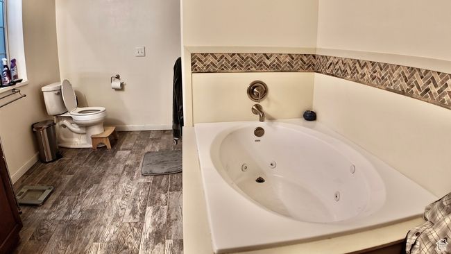 Full bathroom with a whirlpool tub, toilet, wood finished floors, and baseboards | Image 65