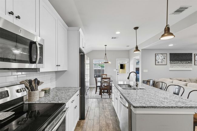Kitchen with stainless steel appliances, a sink, wood finished floors, white cabinetry, and recessed lighting | Image 12